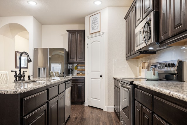 kitchen featuring sink, dark hardwood / wood-style flooring, decorative backsplash, stainless steel appliances, and light stone countertops