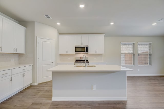 kitchen featuring stainless steel appliances, white cabinetry, sink, and a kitchen island with sink