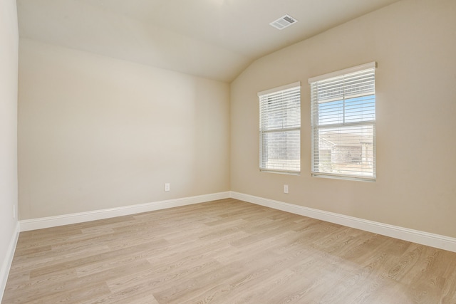 empty room featuring lofted ceiling and light hardwood / wood-style flooring