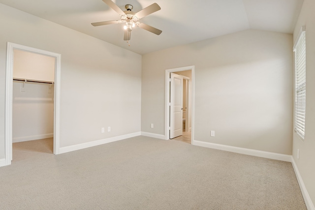 unfurnished bedroom featuring lofted ceiling, ceiling fan, a spacious closet, light colored carpet, and a closet