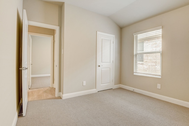 unfurnished bedroom featuring lofted ceiling and light carpet