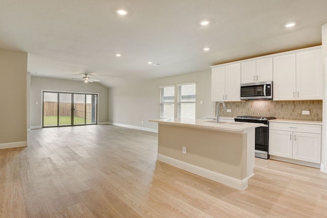 kitchen featuring stainless steel appliances, an island with sink, white cabinets, and decorative backsplash