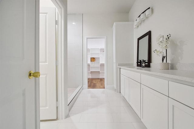 bathroom with walk in shower, vanity, and tile patterned flooring