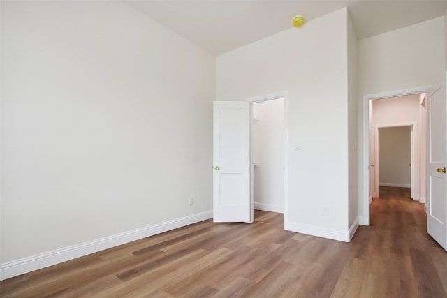 unfurnished bedroom with a towering ceiling and hardwood / wood-style floors