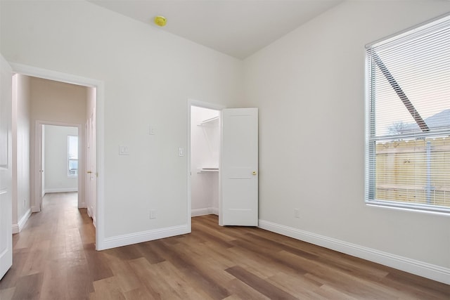 unfurnished bedroom featuring a walk in closet, light hardwood / wood-style floors, and a closet