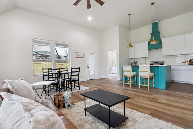 living room featuring hardwood / wood-style flooring, high vaulted ceiling, and ceiling fan