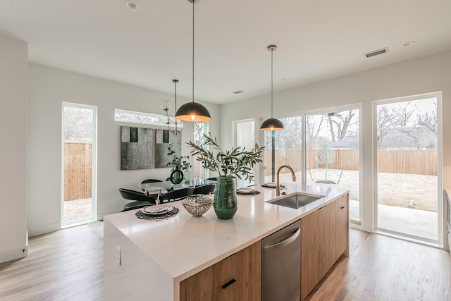 kitchen with light hardwood / wood-style floors, an island with sink, dishwasher, and sink