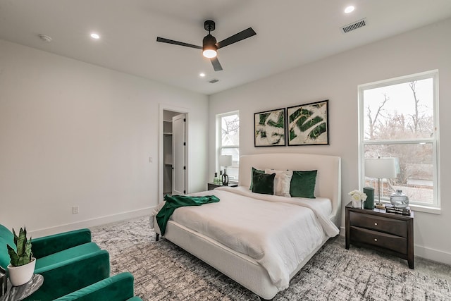 carpeted bedroom featuring a walk in closet and ceiling fan