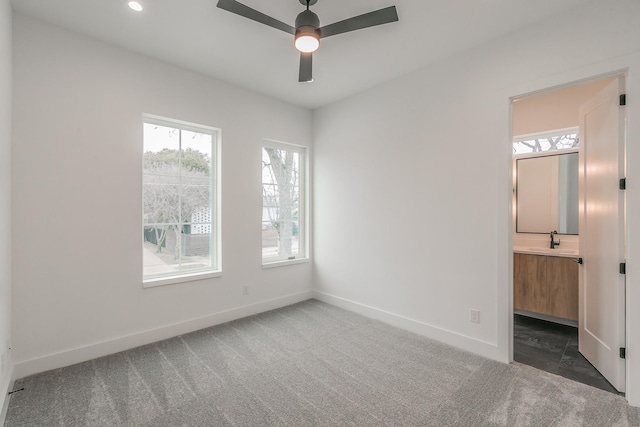 empty room with sink, ceiling fan, and dark colored carpet