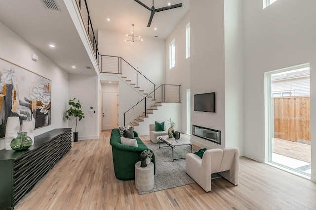 living room featuring an inviting chandelier, light wood-type flooring, and a high ceiling