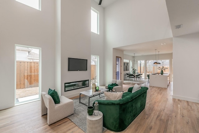 living room featuring a towering ceiling and light hardwood / wood-style flooring