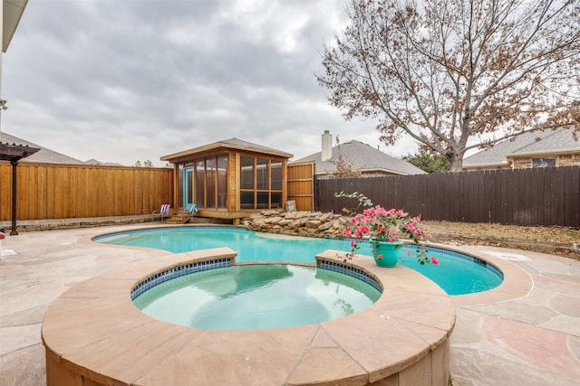 view of pool with an in ground hot tub, a patio, and a sunroom