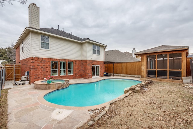 view of pool with an in ground hot tub, a patio area, and a sunroom