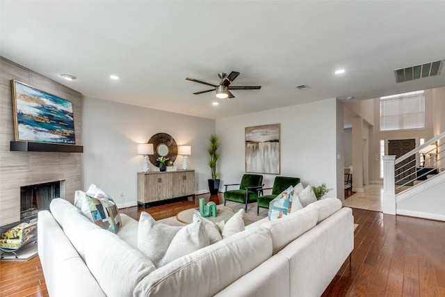 living room with hardwood / wood-style flooring, a tile fireplace, and ceiling fan