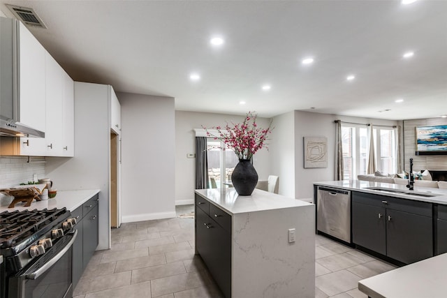 kitchen with white cabinetry, sink, a center island, stainless steel dishwasher, and gas stove