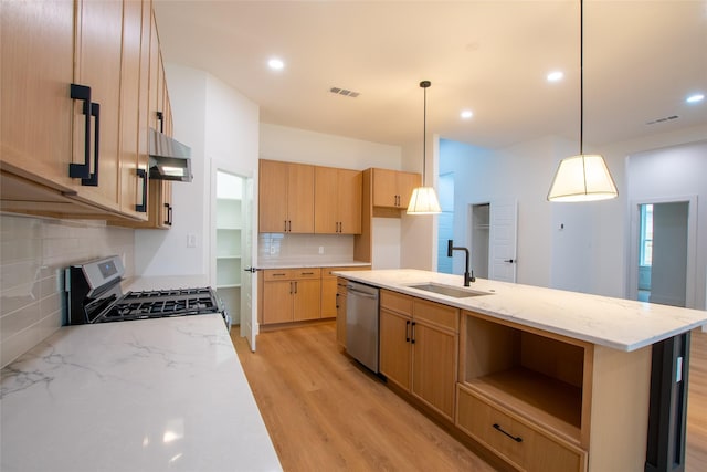 kitchen with appliances with stainless steel finishes, pendant lighting, light brown cabinetry, sink, and a kitchen island with sink