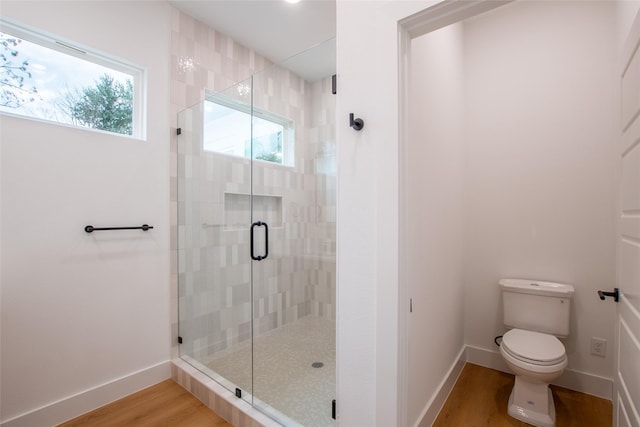 bathroom featuring hardwood / wood-style floors, a shower with shower door, and toilet