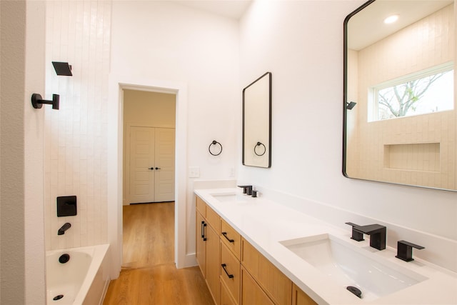 bathroom with tiled shower / bath, wood-type flooring, and vanity