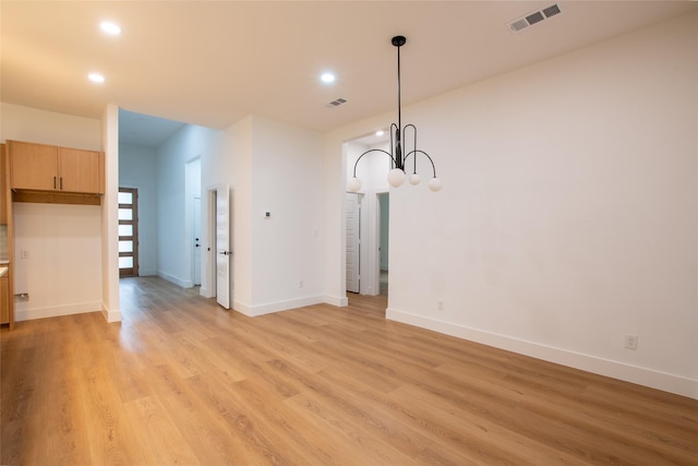 unfurnished dining area with a chandelier and light wood-type flooring