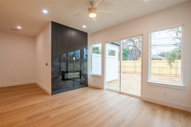 interior space with ceiling fan, a fireplace, and light wood-type flooring