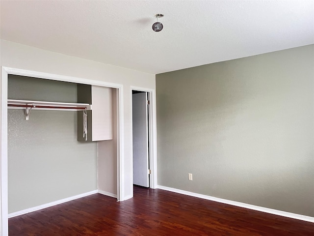 unfurnished bedroom with dark hardwood / wood-style flooring and a closet