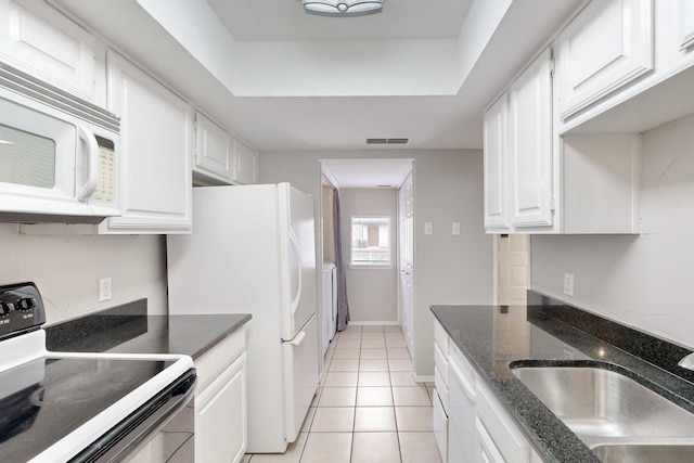 kitchen featuring sink, white cabinets, dark stone counters, light tile patterned floors, and white appliances