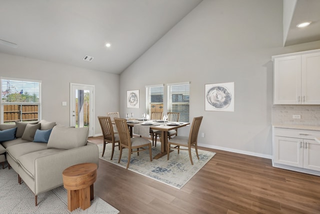 dining area with hardwood / wood-style flooring and high vaulted ceiling