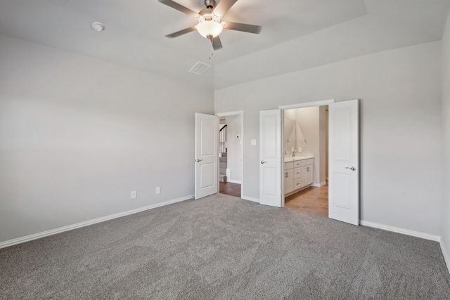 unfurnished bedroom with light carpet, connected bathroom, vaulted ceiling, and ceiling fan