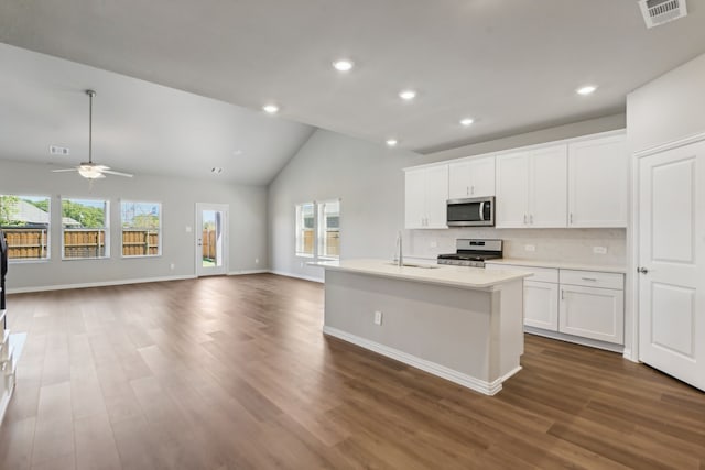 kitchen featuring white cabinetry, vaulted ceiling, a center island with sink, a wealth of natural light, and stainless steel appliances