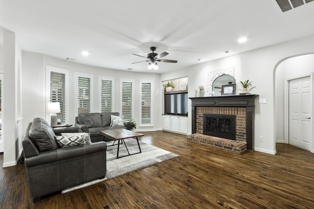 living room with dark wood-type flooring, ceiling fan, and a fireplace