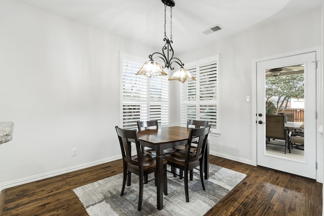 dining area featuring dark wood-type flooring and a notable chandelier