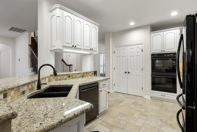 kitchen with white cabinetry, sink, light stone counters, and black appliances