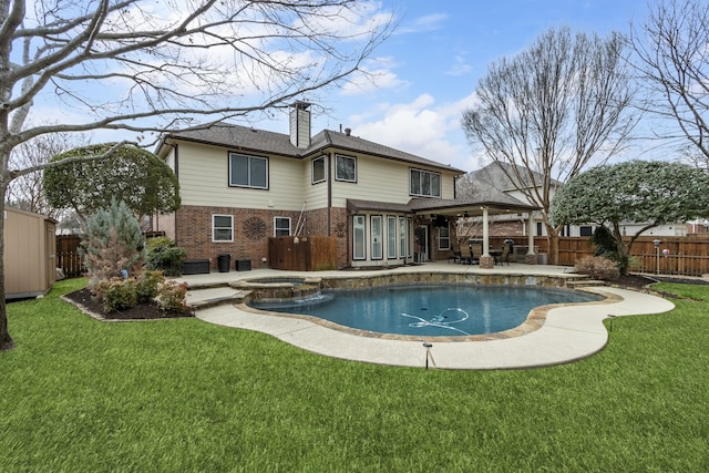 rear view of house with a swimming pool with hot tub, a patio, and a yard