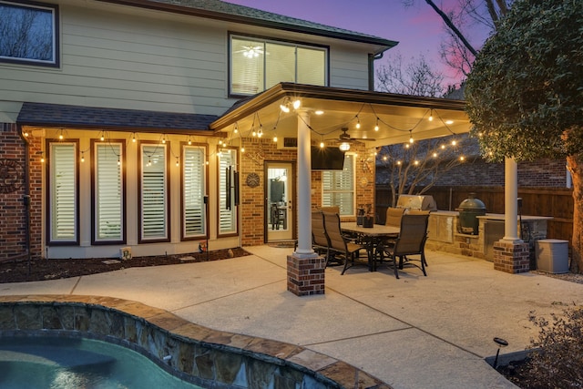 back house at dusk with a patio and ceiling fan