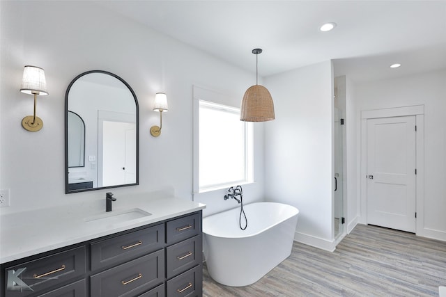 bathroom with hardwood / wood-style flooring, vanity, and a tub