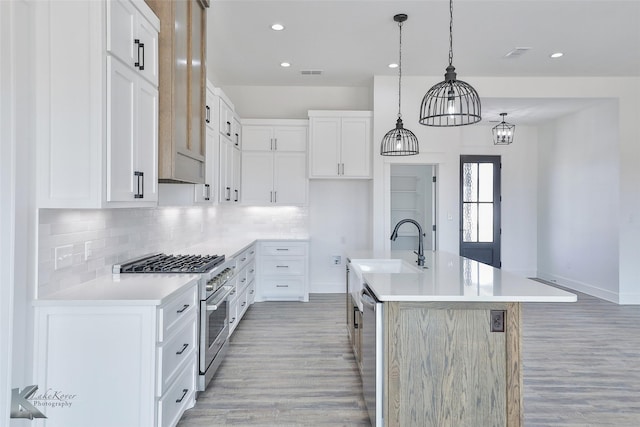 kitchen with white cabinetry, appliances with stainless steel finishes, sink, and an island with sink