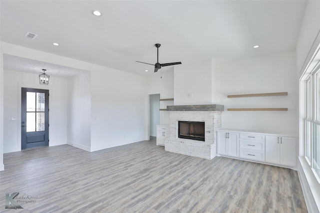 unfurnished living room with ceiling fan, a fireplace, and light hardwood / wood-style flooring