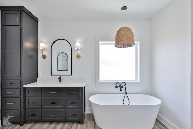 bathroom featuring vanity, hardwood / wood-style floors, and a tub to relax in