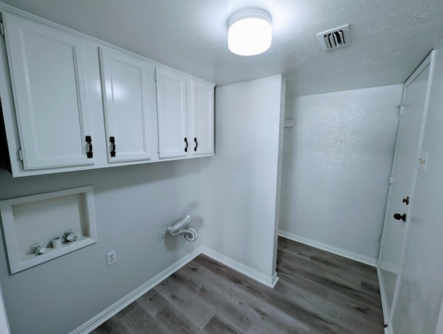 washroom with washer hookup, hardwood / wood-style floors, cabinets, and a textured ceiling