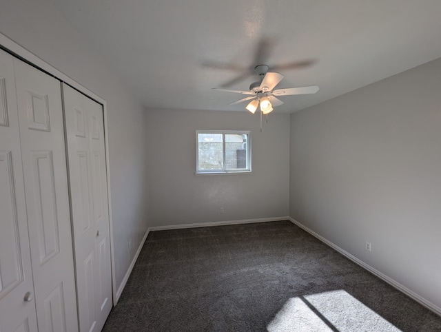 unfurnished bedroom with ceiling fan, dark carpet, and a closet