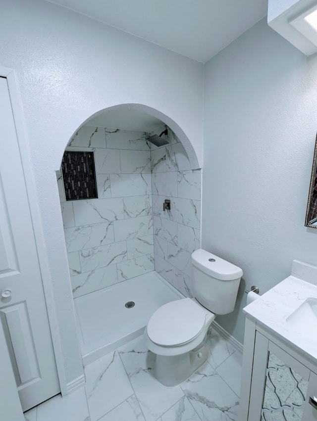 bathroom with vanity, toilet, and a tile shower