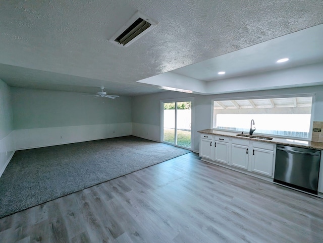 kitchen with white cabinetry, dishwasher, sink, light wood-type flooring, and a textured ceiling