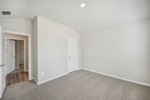 carpeted spare room featuring vaulted ceiling