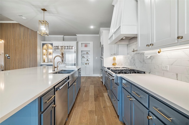 kitchen with appliances with stainless steel finishes, blue cabinets, custom exhaust hood, and white cabinets