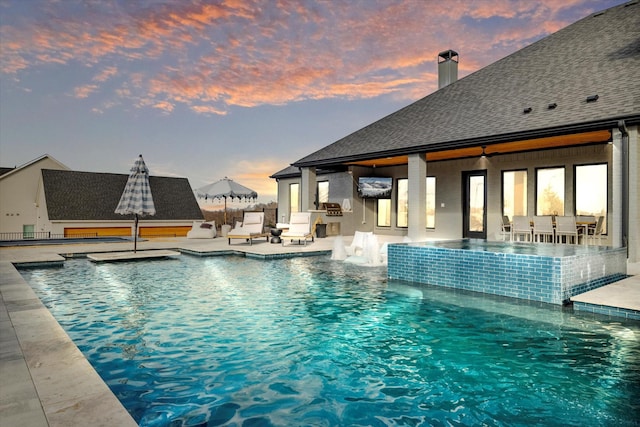 view of swimming pool featuring a patio area, pool water feature, and an outdoor kitchen