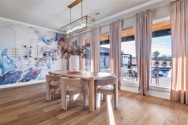 dining room featuring hardwood / wood-style flooring, a wealth of natural light, and ornamental molding