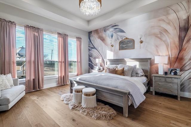 bedroom featuring a notable chandelier, multiple windows, and light wood-type flooring