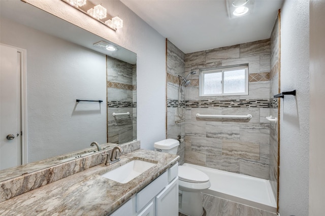 bathroom featuring vanity, tiled shower, and toilet