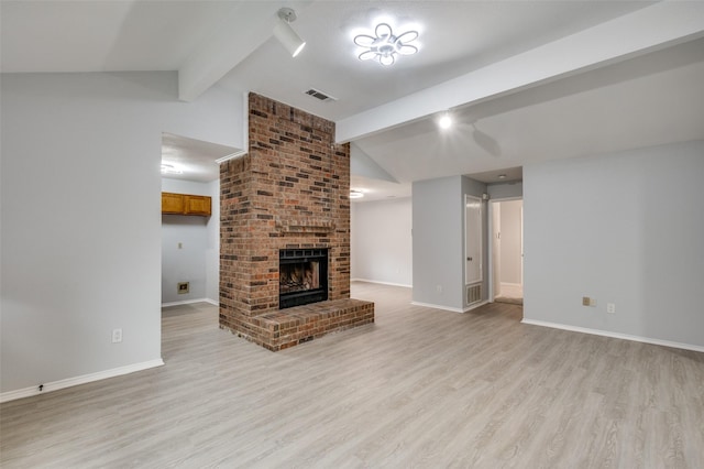 unfurnished living room featuring a brick fireplace, vaulted ceiling with beams, and light hardwood / wood-style flooring