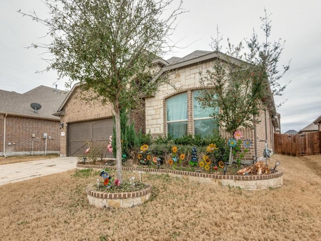 view of front of property with fence, driveway, a garage, stone siding, and brick siding